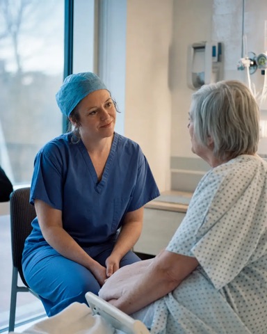 A surgeon talking with an older patient on a ward
